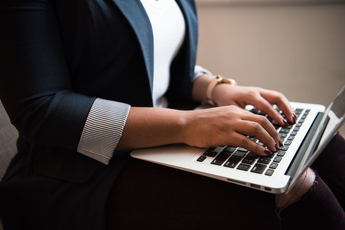 A professional in a blazer typing on a laptop