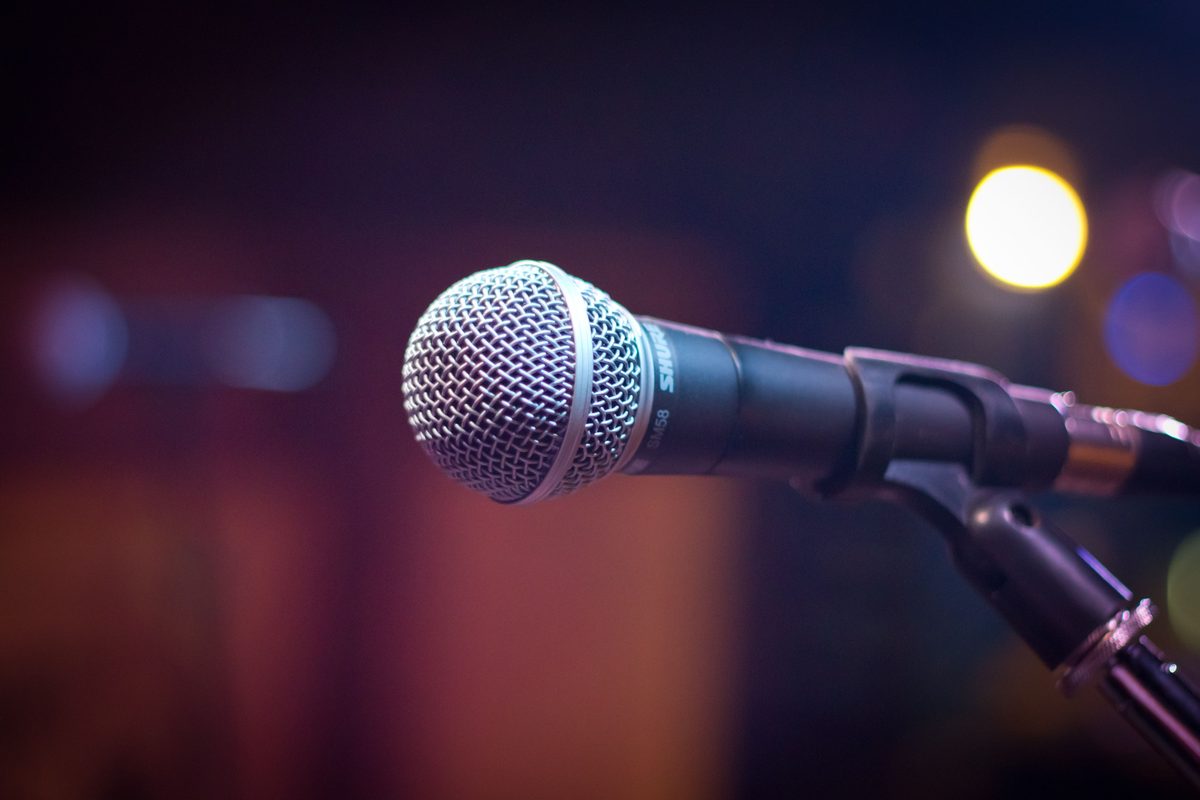 A microphone on a stand under warm stage lights